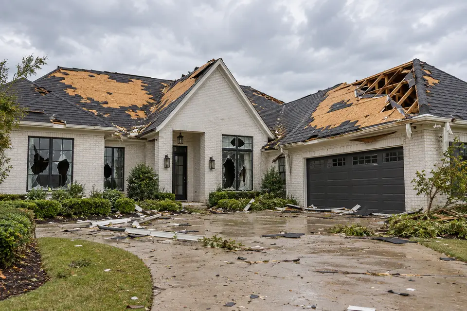 AI-generated illustration of a white brick custom home with extensive roof, window and soffit damage